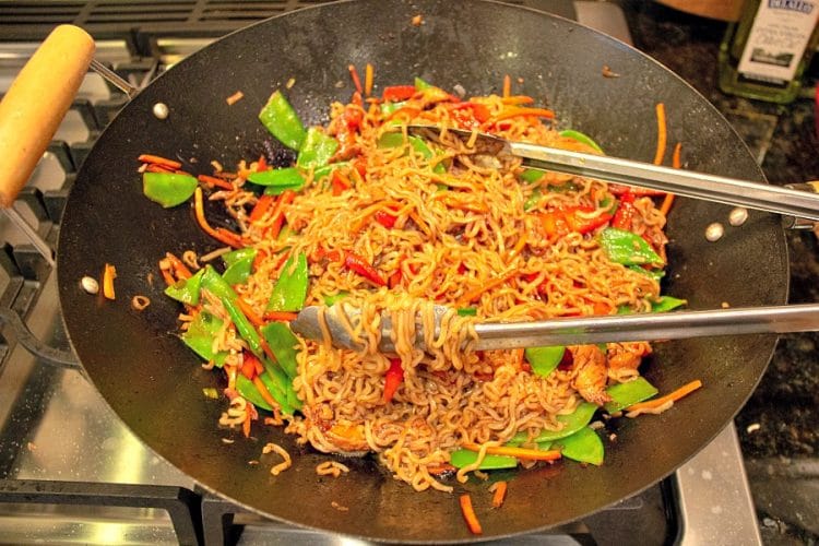 Saltear las verduras y los fideos ramen en un wok